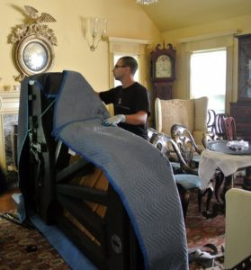 Several moving blankets are placed over and around the piano to give it as much cushioning as possible.