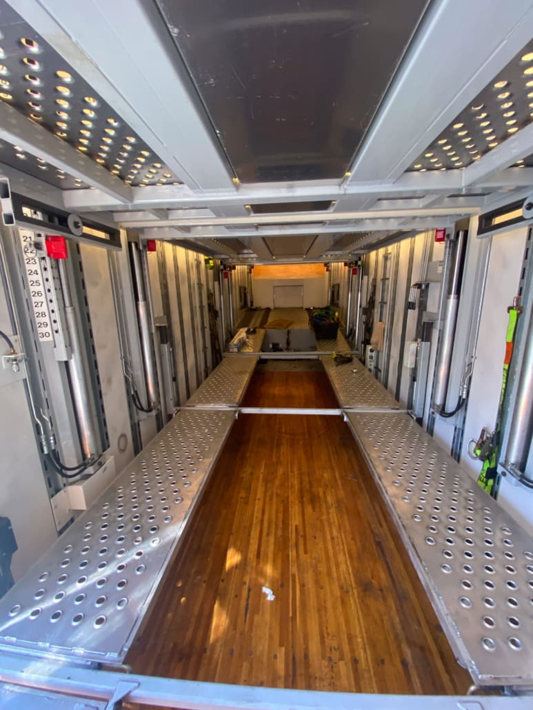 Close-up of the lift-gate mechanism on the enclosed auto transport trailer, highlighting its functionality for easy loading and unloading of vehicles for enclosed auto transport trailers for sale.