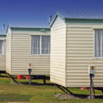 Light yellow mobile homes on grass to illustrate the typical expenses associated with relocating a manufactured home