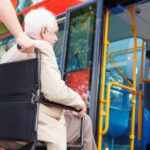 Man in wheelchair being assisted onto a bus, highlighting accessible transportation services in Atlanta GA