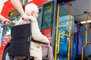 Man in wheelchair being assisted onto a bus, highlighting accessible transportation services in Atlanta GA
