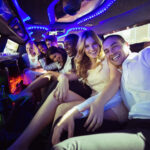 A group of friends joyfully celebrating inside a vibrant limo bus from Xtreme Transportation