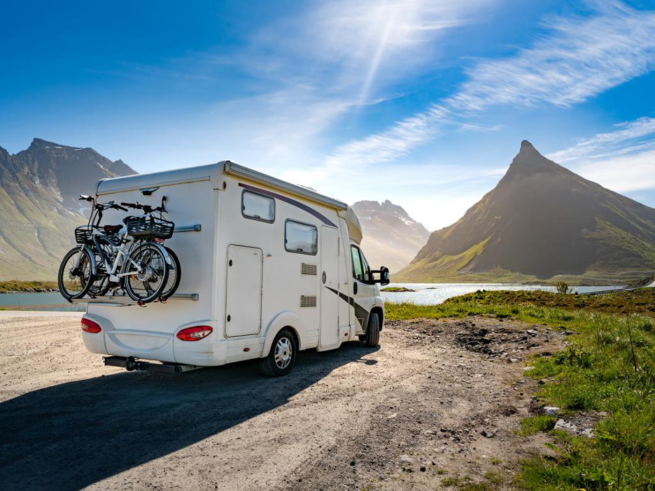 A family relaxing outside their RV by a scenic lake, symbolizing the enjoyment and lifestyle associated with RV ownership and travel.
