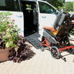 Patient in a Broda chair being wheeled into a van