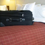 Luggage near a bed in a hotel room, highlighting potential bed bug hiding places