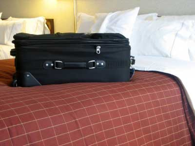 Luggage near a bed in a hotel room, highlighting potential bed bug hiding places