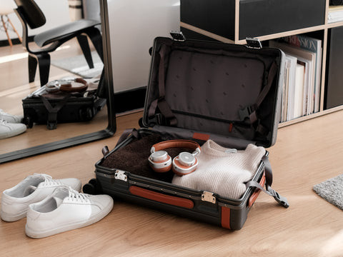 Carry-on suitcase filled packed with folded jumpers and headphones