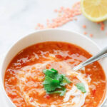 Red lentil and chickpea soup garnished with cilantro and vegan yogurt, showcasing its rich texture