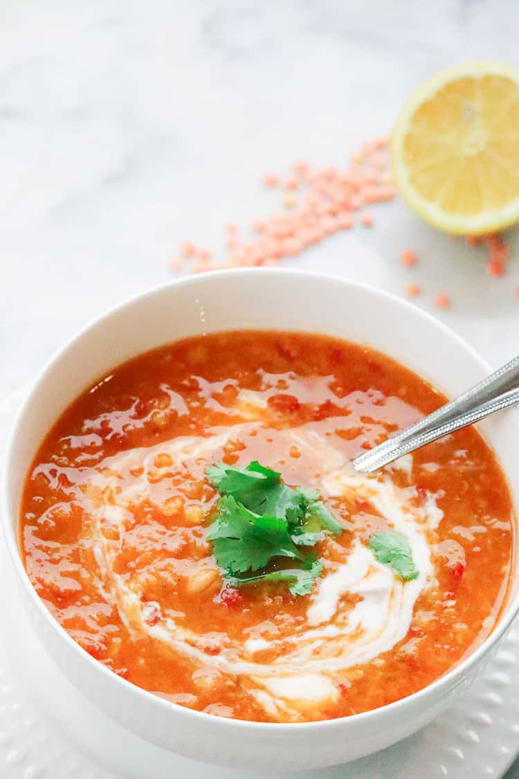 Red lentil and chickpea soup garnished with cilantro and vegan yogurt, showcasing its rich texture