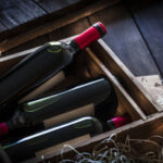 Red wine bottles packed in a wooden box shot rustic wooden table